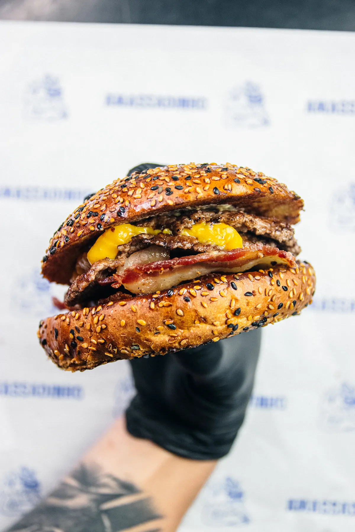 Burger do Amassadinho montado na mão, com bacon e queijo