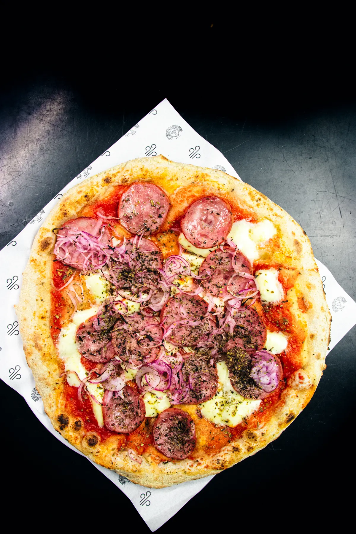 Pizza da Sopro Forneria servida no papel da casa